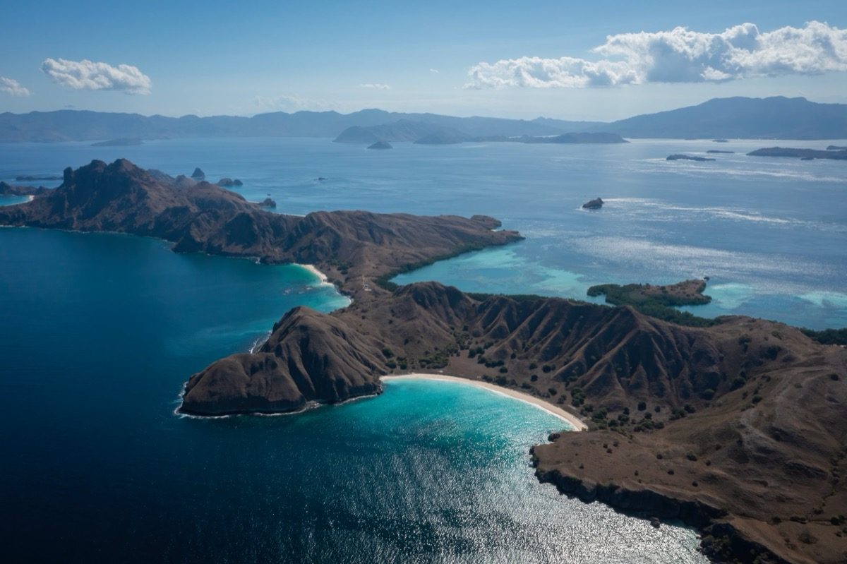 Vista aérea de una isla de colinas secas con bahías de arena blanca y agua turquesa en el Parque Nacional de Komodo