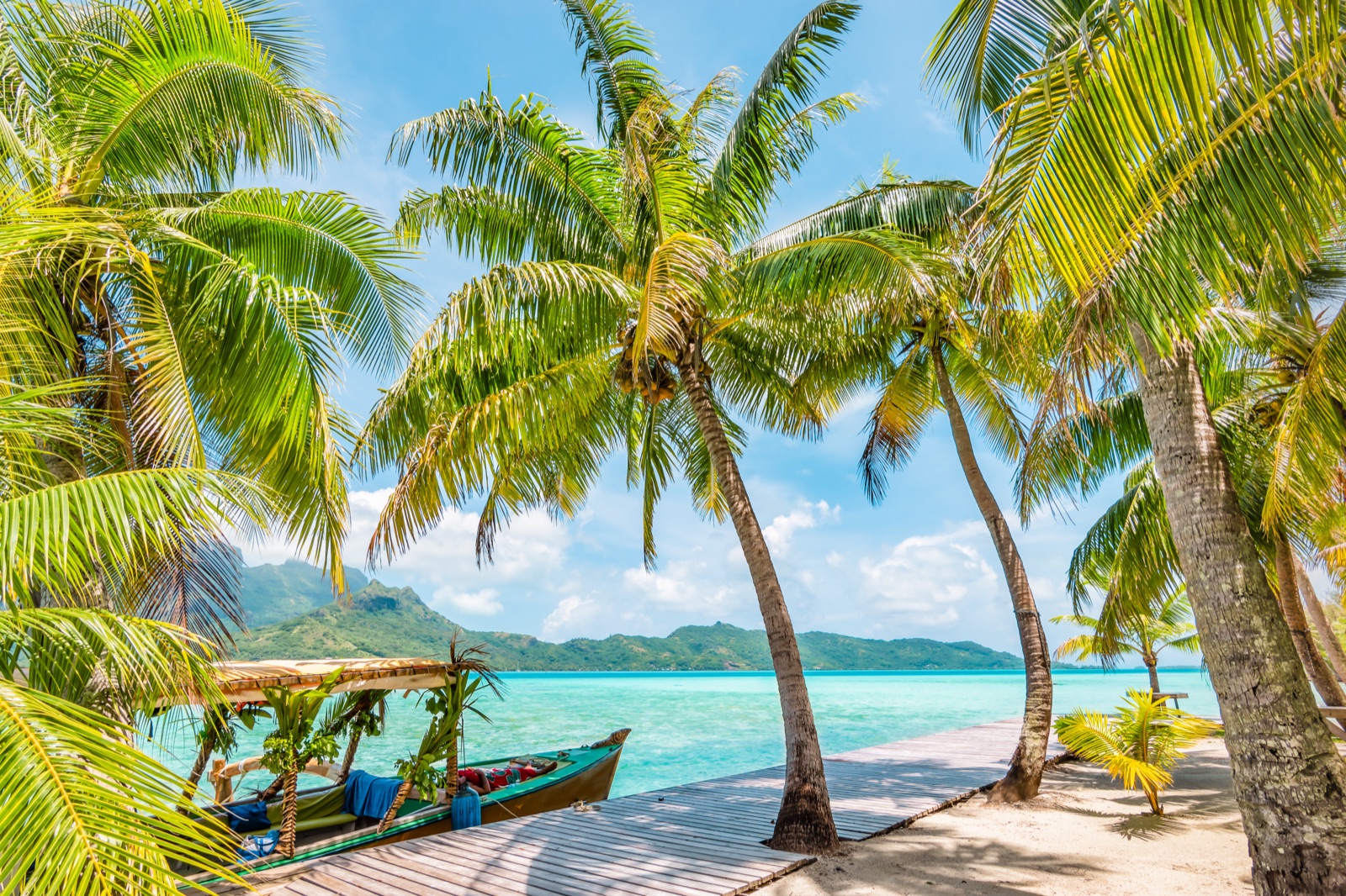 Palmeras sobre una playa y barca amarrada en la laguna de Bora Bora